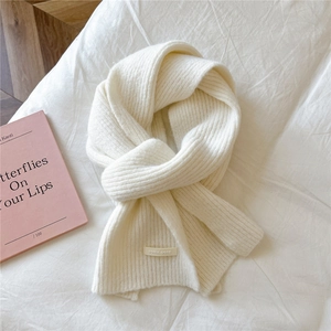 Close-up of soft knit scarf texture and branded label on warm cream fabric