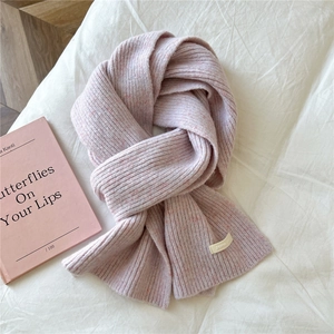 Close-up of light pink ribbed knit scarf texture with soft fabric and decorative side label