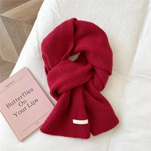 Close-up of vibrant red knitted scarf with soft texture and brand label detail