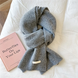 Close-up of grey knitted scarf with soft vertical texture and stitched brand label