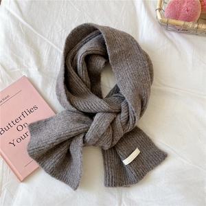 Close-up of thick ribbed knit scarf in dark grey with a minimalist brand label detail