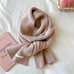 Close-up of chunky knit texture and woven brand label on a soft pink beige scarf
