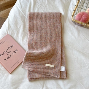 Detail of light pink rib-knit scarf showing wool blend texture and brand label