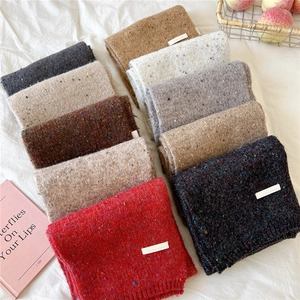 Flat lay of thick knitted scarves in various colors with textured nep yarn and logo tags