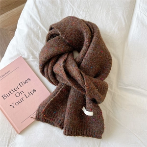 Detail of dark brown knitted scarf with colorful flecks and a small white woven label