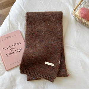 Detail of dark brown speckled knit scarf with ribbed cuff and white logo label