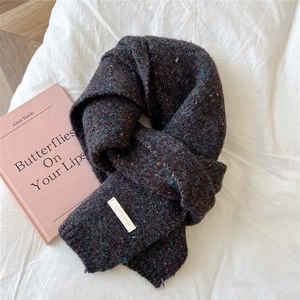 Close-up of thick dark grey speckled knit scarf with a rectangular brand label detail