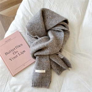Detailed close-up of grey knitted scarf texture with logo tag and care label