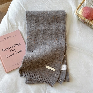 Close-up of a grey tweed knit scarf with colorful flecks and a small brand label