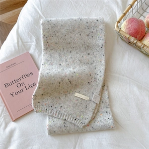 Detail of light gray knit scarf with wool blend texture and colorful speckled yarn