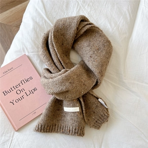 Close-up of caramel brown knit scarf with colorful tweed texture and white woven label