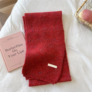 Detail of red thick knitted scarf with colorful tweed specks and ribbed edges on cloth