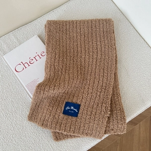 Detail of coffee brown knit scarf with thick ribbed texture and brand woven label
