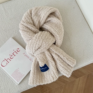 Detailed close-up of beige thick plush scarf texture with a blue vintage woven brand tag