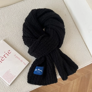 Detailed macro view of black thickened warm scarf with soft texture and blue woven label