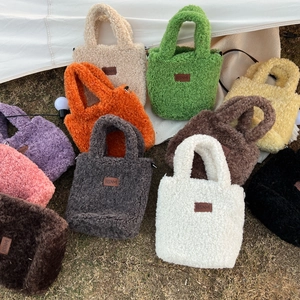 Chic plush faux fur tote bags in vibrant colors with leather patch on dry grass background