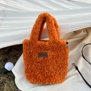 Detail of orange plush handbag with brown leather logo patch and metal D-ring strap