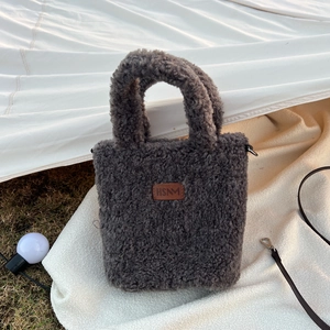 Detail of dark gray faux fur handbag with HSNM leather patch and metal D-ring buckle