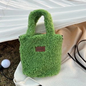 Detail of green fleece tote bag with brown leather HSNM logo and metal strap hooks
