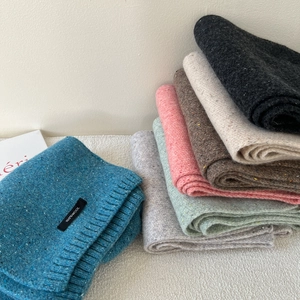 Close-up of assorted knit wool scarves with 100 percent wool label and soft textures