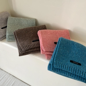 Five assorted colors of 100% wool knitted scarves displayed on a white staircase