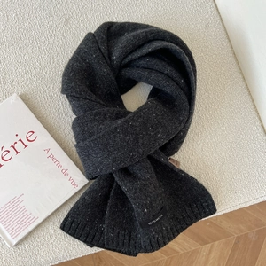 Detail of 100% pure wool dark grey knitted scarf with subtle white snowflake texture