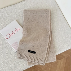 Detail of 100% wool beige knit scarf showing premium ribbed texture and material tag