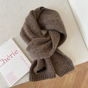 Detailed macro view of dark brown mixed wool knit scarf with 100% wool label and ribbing