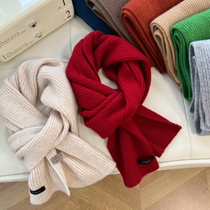 Thick 100% wool knitted scarves in multiple colors arranged on a vintage suitcase