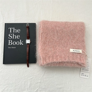 Detailed macro shot of soft pink alpaca wool knit scarf with ALPACA label and tag