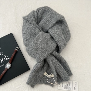 Detail of fluffy grey alpaca knit scarf texture with a white product tag and luxury props