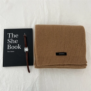 Close-up of a 100% wool knitted scarf in camel brown showing the ribbed texture and label