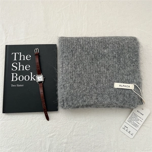 Detail of grey knitted alpaca scarf with textile label showing soft fuzzy texture