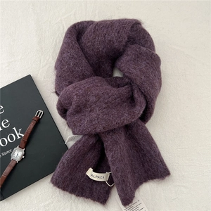 Detailed texture of purple alpaca knit scarf with brand label and lifestyle accessories