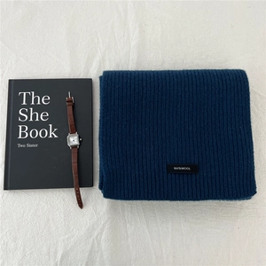 Detailed close-up of 100% wool scarf texture with material label in deep blue knit
