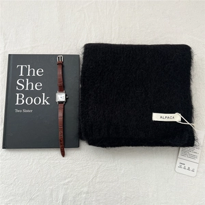 Close-up of black alpaca knit scarf texture with material label and washing instructions