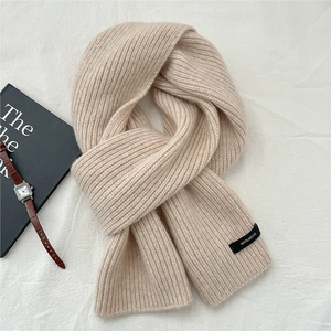 Detailed close-up of 100% wool label on thick beige knitted winter scarf with soft texture