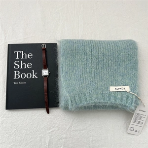 Detail of light blue knitted alpaca wool scarf texture with brand label and tags