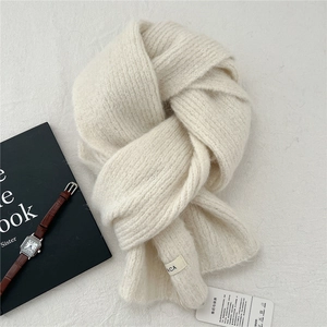 Detailed close-up of cream knitted scarf texture with fabric label and care tag