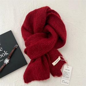 Detail of soft alpaca knit scarf in deep red featuring luxury texture and fabric label