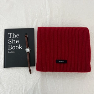 Detailed view of red 100% wool scarf showing thick knit texture and material tag