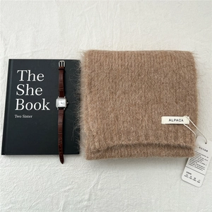 Close-up of thick brown alpaca wool knitted scarf with soft fuzzy texture and brand tag