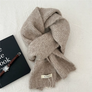 Detail shot of oatmeal alpaca wool knitted scarf texture with product tag and accessories