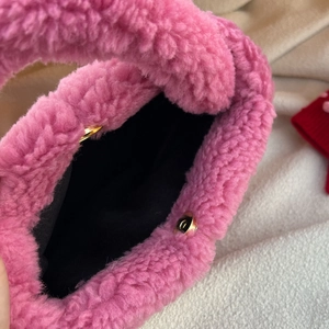 Detailed close-up of pink faux shearling handbag showing magnetic gold clasp and black lining