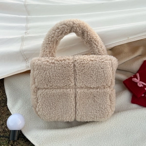 Detail of beige teddy fleece handbag showing soft cross-stitched texture and sturdy handle