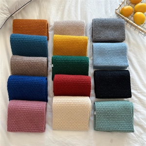 Chunky knit scarf collection in multiple solid colors displayed on textured linen