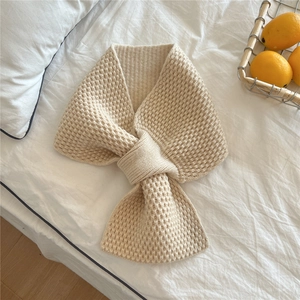 Detail of beige knitted scarf featuring a textured waffle pattern and cross-over loop