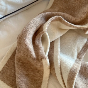 Gros plan sur la texture épaisse d'une écharpe tricotée beige et blanc en tissu doux