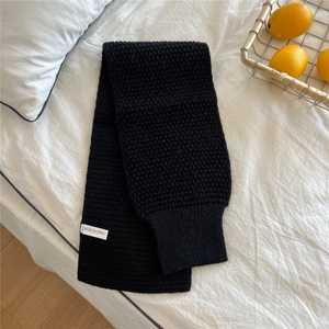 Detail of black chunky knit scarf featuring honeycomb texture and ribbed end cuff