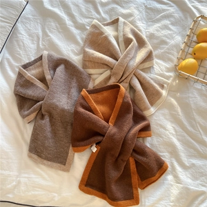 Trois écharpes en maille douce aux tons beige et marron sur tissu blanc